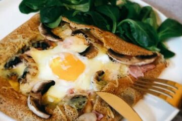 Galette de sarrasin garnie d'un œuf, de champignons et de jambon, servie avec de la mâche